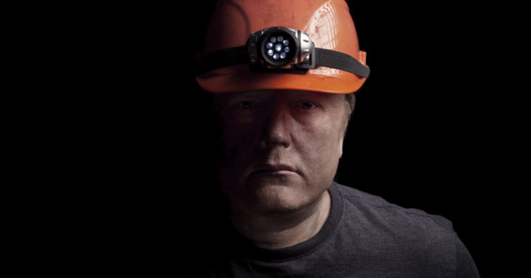 portrait of a man with a hard hat looking solemn.