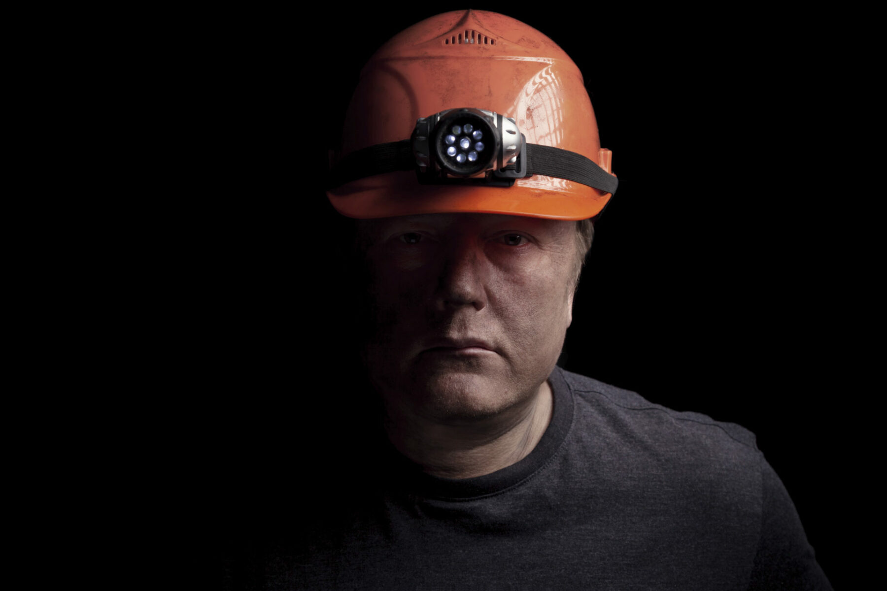 portrait of a man with a hard hat looking solemn.