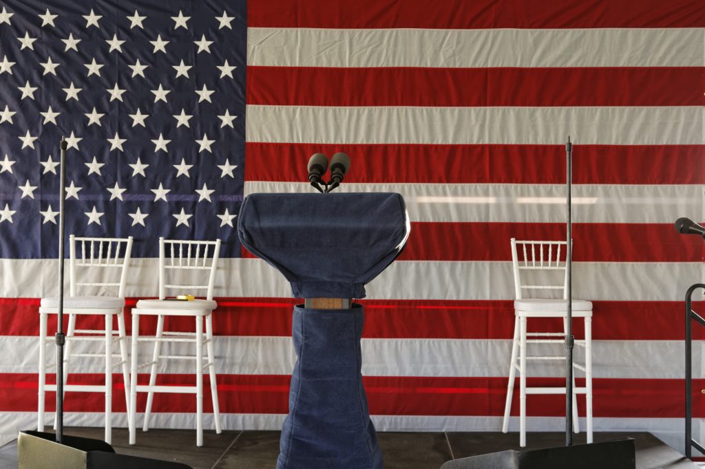 empty speech podium with american flag and empty chairs
