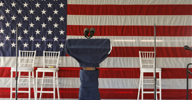 empty speech podium with american flag and empty chairs