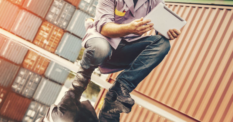 construction worker crouched down at a doc looking at a notebook