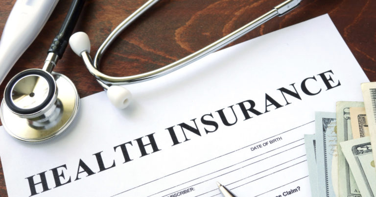 health insurance form on table with money and a stethoscope