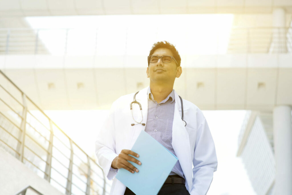 Portrait of Asian Indian medical doctor standing outside hospital building