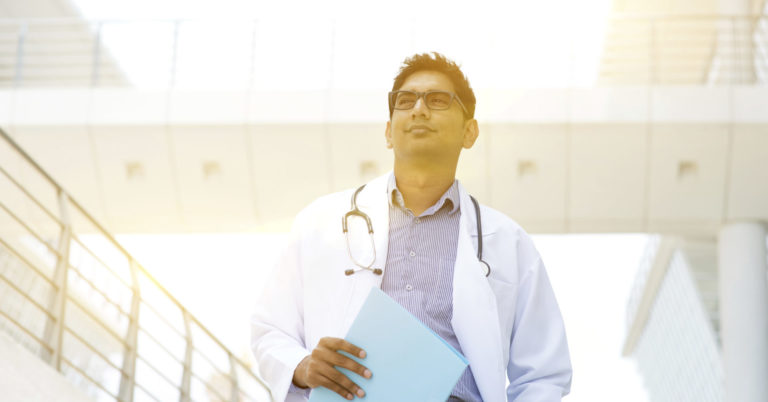 Portrait of Asian Indian medical doctor standing outside hospital building