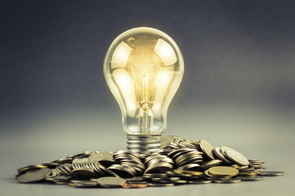 lightbulb lit above coins showing power of energy.