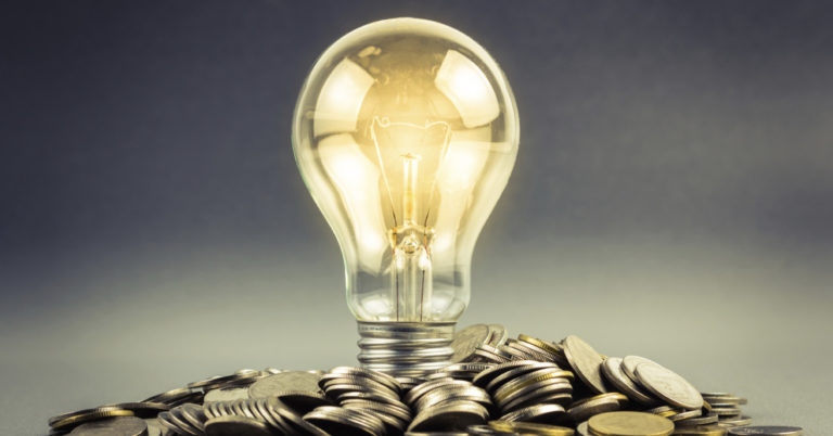 lightbulb lit above coins showing power of energy.