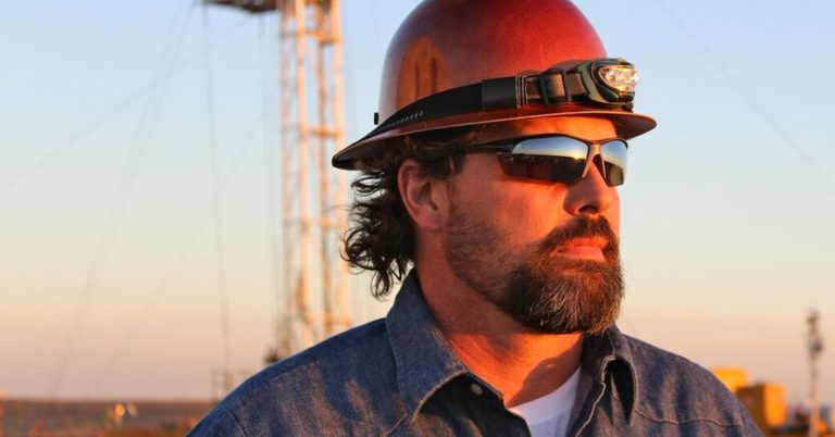 construction worker with sunglasses looking forward with blue sky in the background