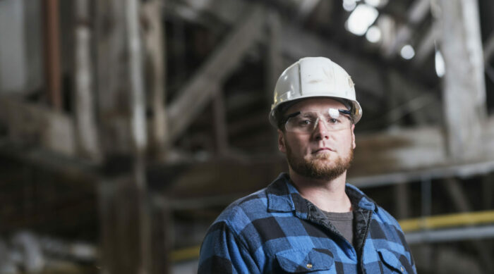 Man wearing hardhat, safety goggles and plaid shirt