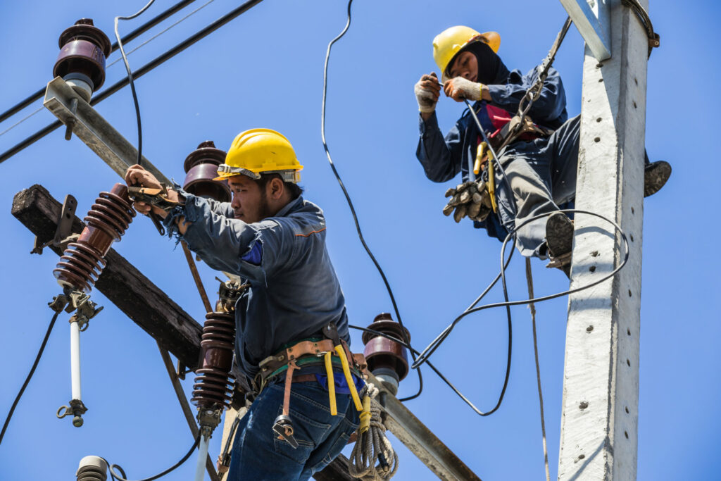 Electricians working together on the electricity pole