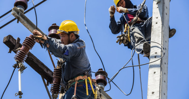 Electricians working together on the electricity pole