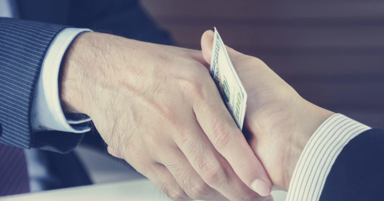 Handshake of businessmen with money