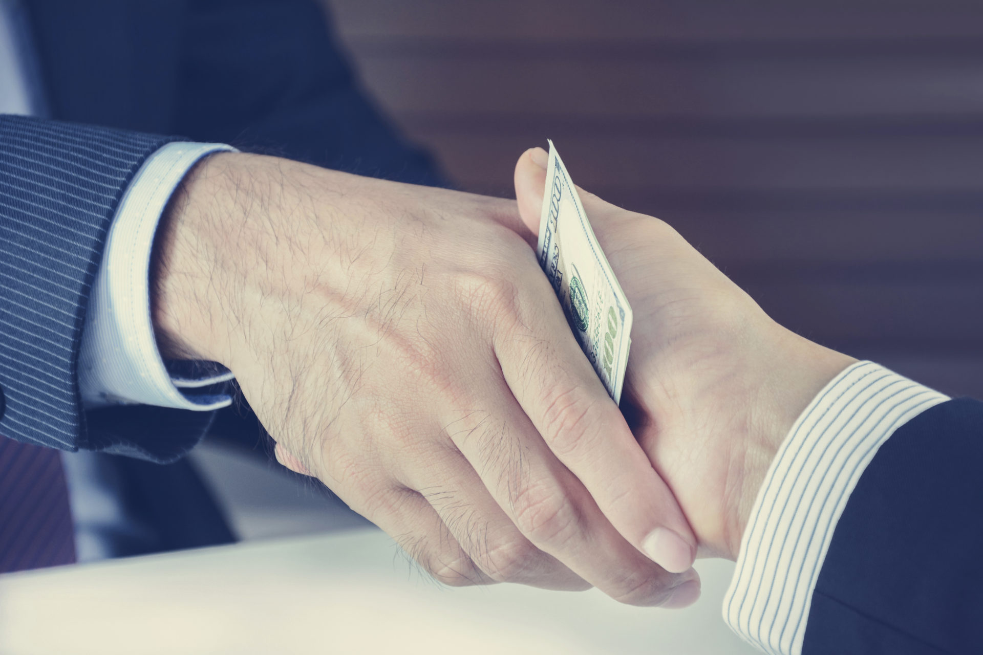 Handshake of businessmen with money