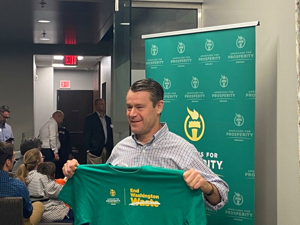 Senator Todd Young holds up one of Americans for Prosperity's End Washington Waste t-shirts at an event with activists and AFP President Tim Phillips