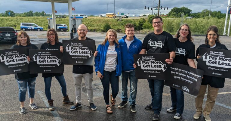 Activists hold up signs a True Cost of Washington Tour event in Fredericktown, Missouri. Activists came to lower the cost of gas in 2022 to $2.12, the price a year ago when President Joe Biden was inaugurated.