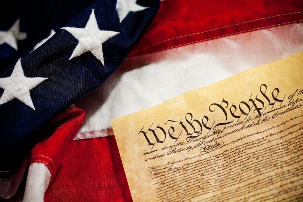 The U.S. Constitution "We the People" preamble beneath an American flag
