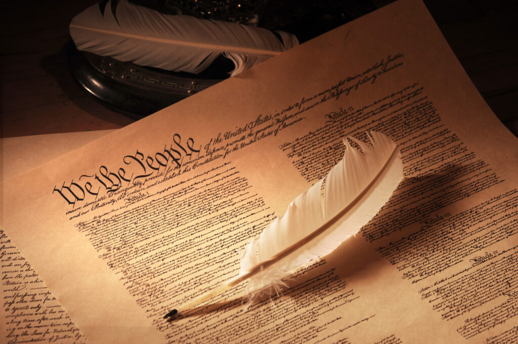 A quill pen resting on the U.S. Constitution